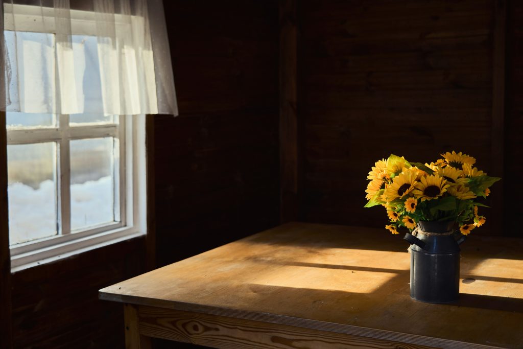 Holztisch in einem fränkischen Wirtshaus mit Blumenstrauß im Tageslicht. Schlichte Atmosphäre, Ruhe und Verlässlichkeit als Teil der Wirtshauskultur rund um Lichtenfels.