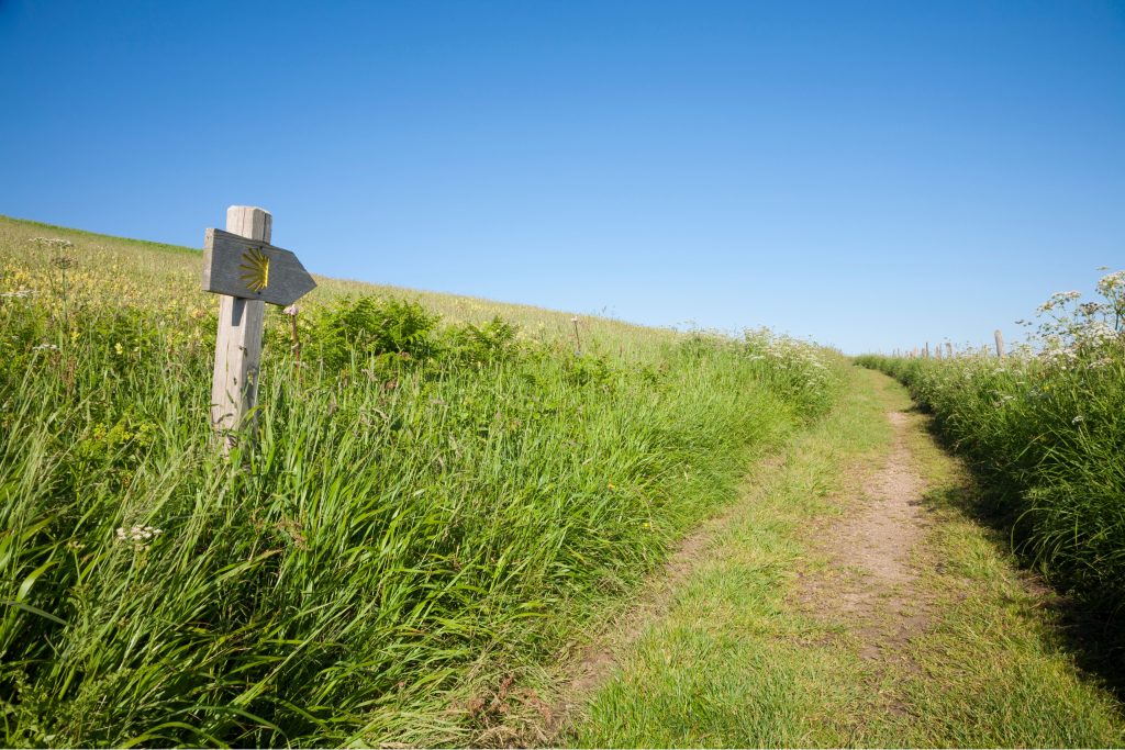 Pilgerweg mit Wegzeichen und Kreuzsymbol in einer Landschaft