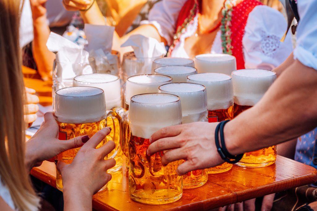 Menschen stoßen bei einem fränkischen Sommerfest gemeinsam mit Bierkrügen an.