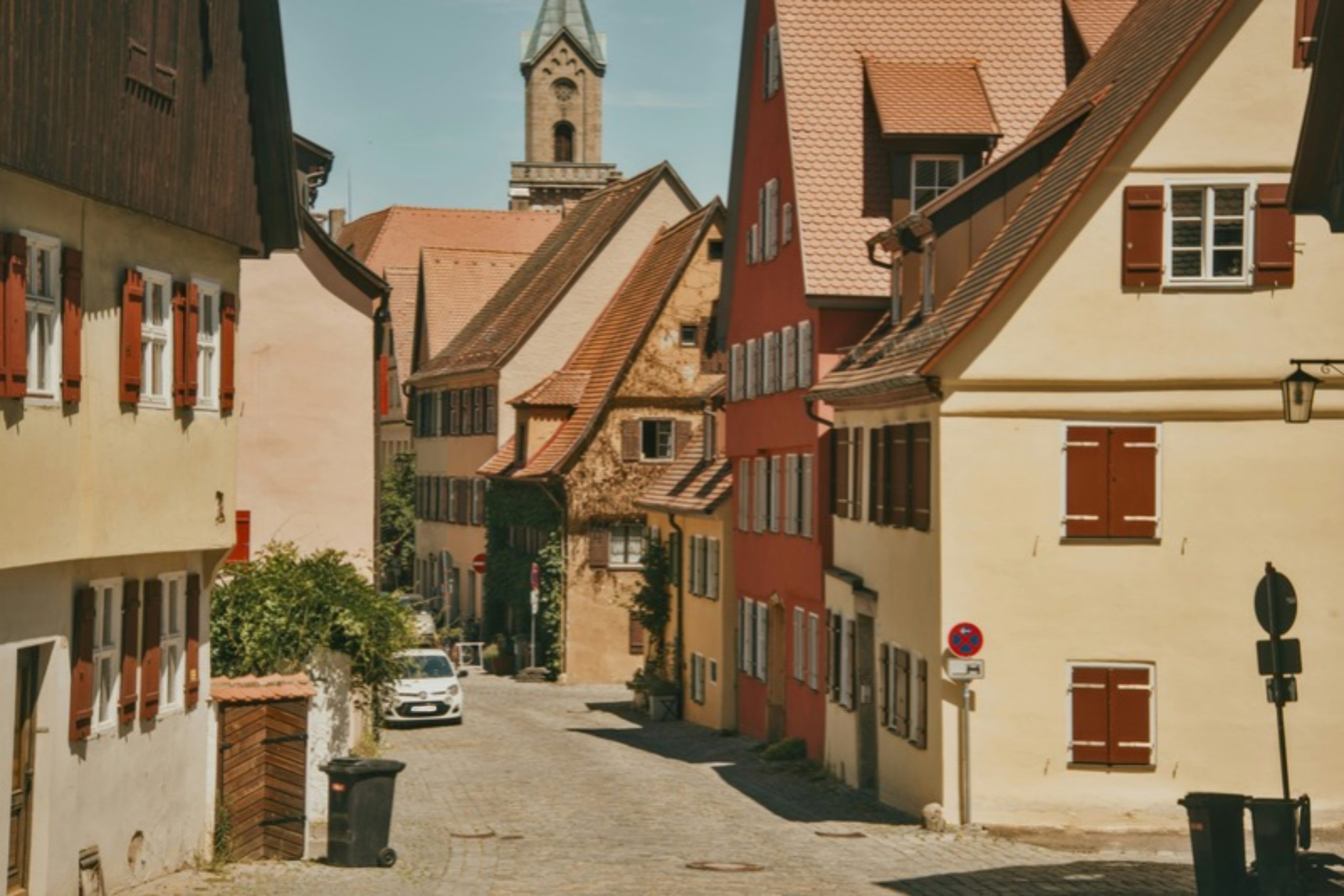 Historischer Ortskern mit schmaler Straße, alten Häusern und Kirche im Hintergrund